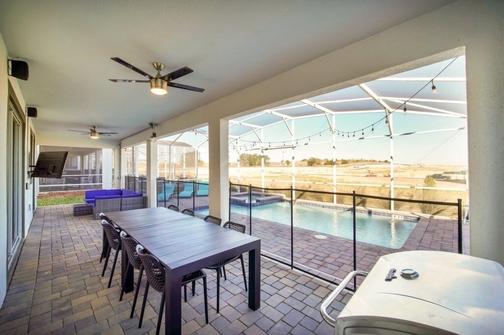 An outdoor patio area with a pool, seating, and a table.