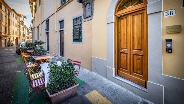 A narrow street with a row of outdoor tables and chairs, a wooden door with the number 36, and a sign for "Nerone" restaurant. - Residenza Fanti (Florence)