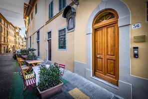 A narrow street with a row of outdoor tables and chairs, a wooden door with the number 36, and a sign for "Nerone" restaurant. - Residenza Fanti (Florence)