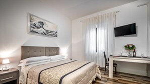 A hotel room with a bed, bedside table, TV, and a desk with a chair. - Residenza Fanti (Florence)