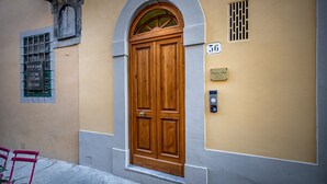 A wooden door with a small window above it, a number plaque, and a small vent on the wall. - Residenza Fanti (Florence)