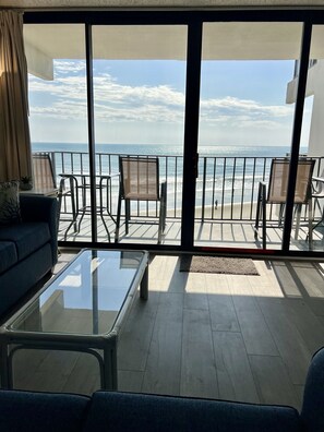 A balcony with a view of the sea, furnished with a sofa, chairs, and a glass table. - Royal Garden Resort 301 3 Bedroom Condo by RedAwning (Murrells Inlet)