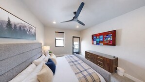 A bedroom with a bed, a ceiling fan, a mounted TV, and a window. - Jordanelle Mountain Paradise 204 3 Bedroom Condo by RedAwning (Heber City)