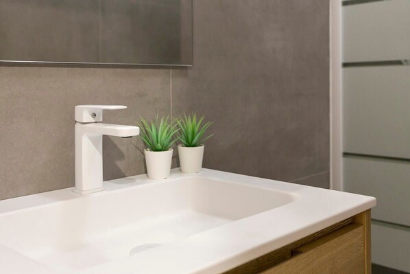 A modern bathroom with a white sink, two potted plants, and a large mirror above the sink. - The Collection - Poblenou 3BD Next to the Beach (Barcelona)