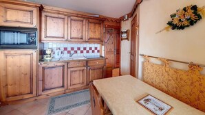 A compact kitchen with wooden cabinets, a microwave, and a tiled backsplash. - Ski-in/ski-out & foot of the slopes, 2nd floor, balcony, 45m², Les Menuires (Les Menuires)