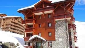 A multi-story wooden chalet with balconies, a stone facade, and a sign indicating it is a chalet. - Ski-in/ski-out & foot of the slopes, 2nd floor, balcony, 45m², Les Menuires (Les Menuires)