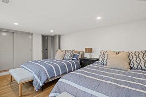 A bedroom with two beds, a bedside table, a lamp, and a wardrobe.