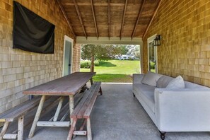 Uma área de varanda coberta com mesa de madeira e sofá.