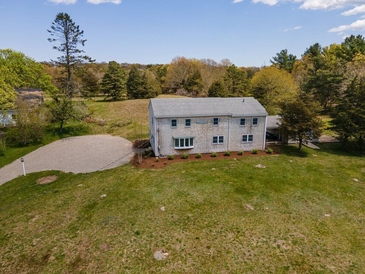A two-story house with a paved driveway and a lawn.