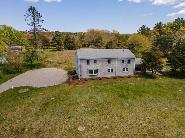 A two-story house with a paved driveway and a lawn.