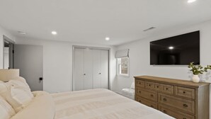 Un dormitorio con cama, cómoda y televisor de pantalla plana en la pared.