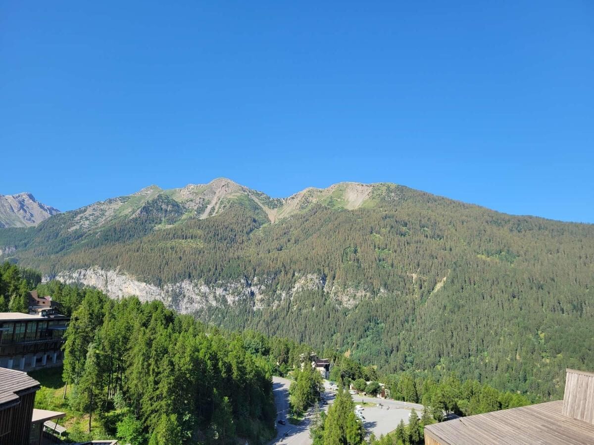 A mountain landscape with a building in the foreground and a clear sky.