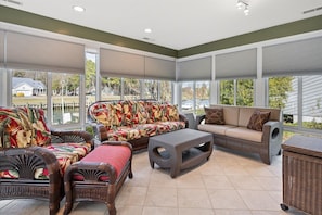 A sunroom with wicker furniture, large windows, and a view of the outside.