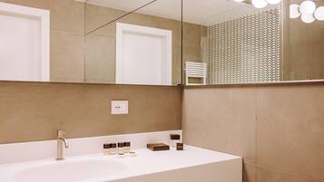 Un bagno con un lavandino bianco, uno specchio e un portascopevoli.