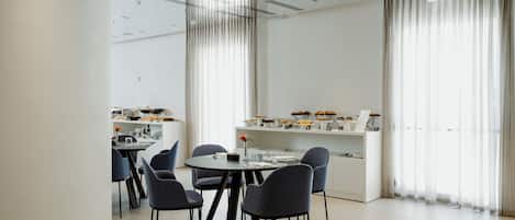 A modern dining area with a round table, four chairs, and a white counter with food displays.