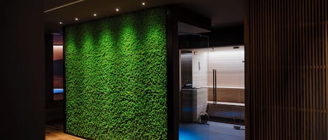 Interior moderno com parede de jardim vertical verde, piso de madeira e divisória de vidro.