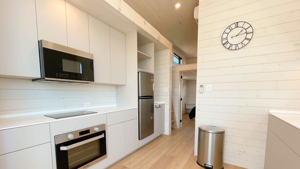 A modern kitchen with built-in appliances, a stainless steel refrigerator, and a trash bin. - The Phoenix (Cañon City)