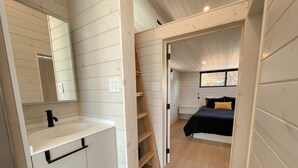 A bedroom with a bed, a bedside table, and a window. - The Phoenix (Cañon City)