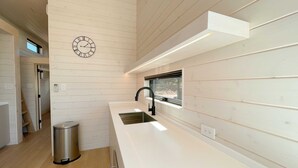 A modern kitchen with a built-in sink, a window, and a wall-mounted clock. - The Phoenix (Cañon City)