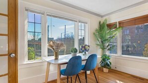 Un coin repas avec une table blanche, deux chaises bleues et une plante en pot.