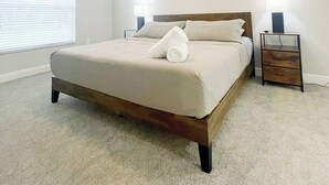 A bedroom with a bed, a ceiling fan, bedside lamps, and a nightstand. - Comfy and Cozy 4 bedroom home with garage (Ocala)