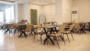 A spacious dining area with multiple tables and chairs, a large mirror, and a decorative wall with greenery. - HOME PLUS HOTEL (Istanbul)