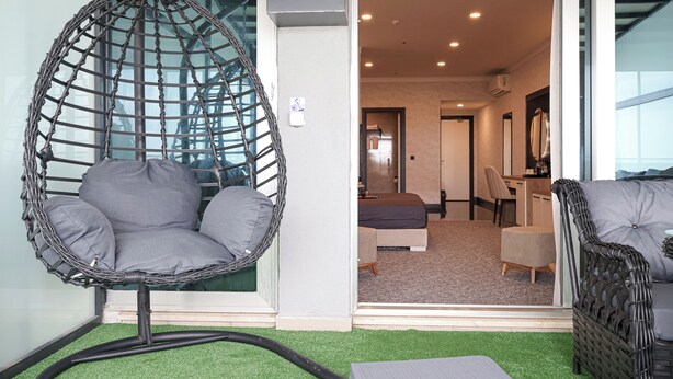A room with a hanging chair, a sofa, and a bed. - HOME PLUS HOTEL (Istanbul)