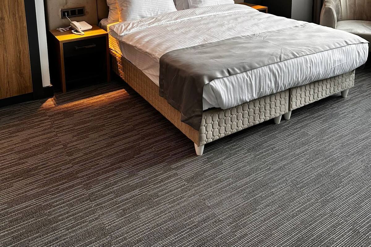 A hotel room with a large bed, two bedside tables, a chair, and wall-mounted lighting.