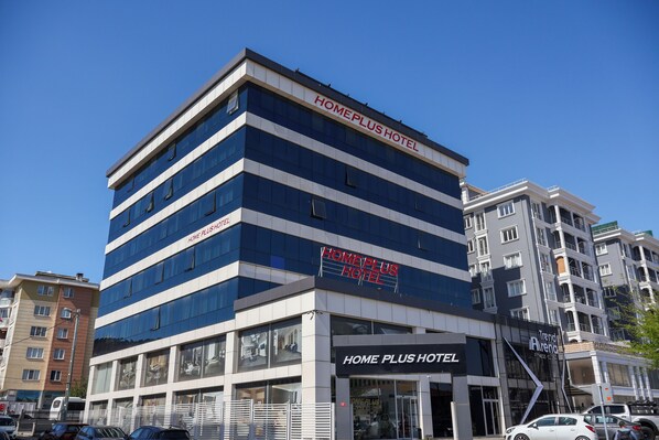 A multi-story hotel with a prominent 'Home Plus Hotel' sign.