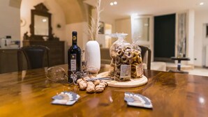 A dining table with a bottle of wine, a vase with dried plants, and a basket of snacks. - [Sassi-Suite]- Aura - Matera (Milano)