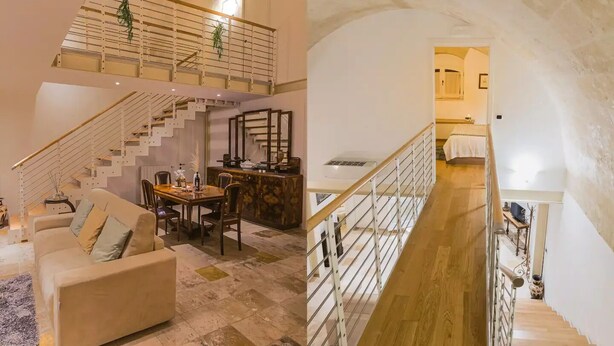 A spacious living area with a sofa, dining table, and a staircase leading to an upper level. - [Sassi-Suite]- Aura - Matera (Milano)