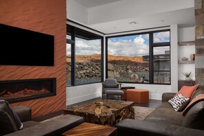 Ein modernes Wohnzimmer mit Kamin, großen Fenstern und einer Steinwand.
