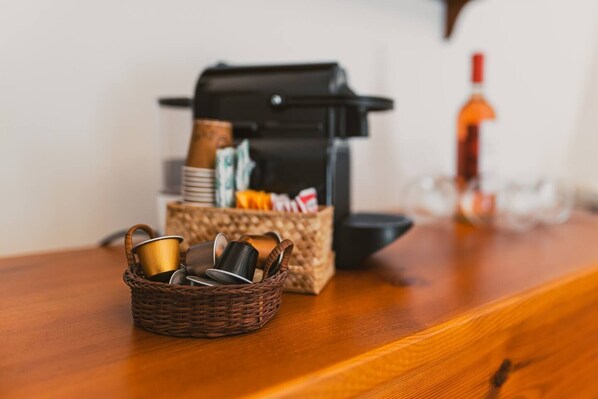 A coffee machine, a basket with cups, and a bottle on a wooden table. - Intrulloves- Complex of Trulli Storici Pugliesi (Milano)