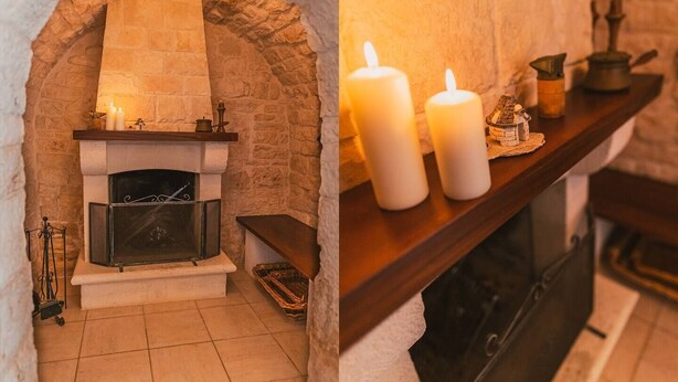 A stone fireplace with a mantel, candles, and a small shelf with decorative items. - Intrulloves- Complex of Trulli Storici Pugliesi (Milano)