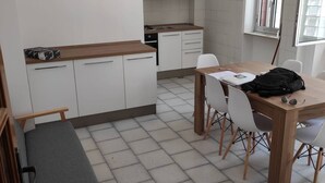 Una cocina compacta con armarios blancos y encimera de madera. Se observa una mesa de comedor con sillas y un banco.