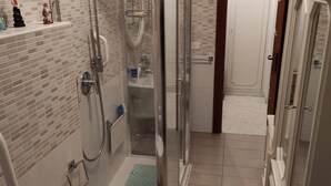 Un baño moderno con ducha de vidrio, lavamanos y retrete.