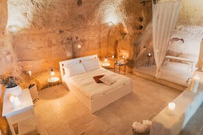 A cozy bedroom with a bed, bedside tables, a bench, and a small table with candles. - [Sassi-Suite] ❉ InLapis - the cavehouse ❉ (Milano)