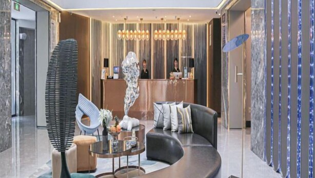 A modern lobby with a reception desk, seating area, and decorative elements. - Crystal Orange Xu Zhou Su Ning Guang Chang (Xuzhou)