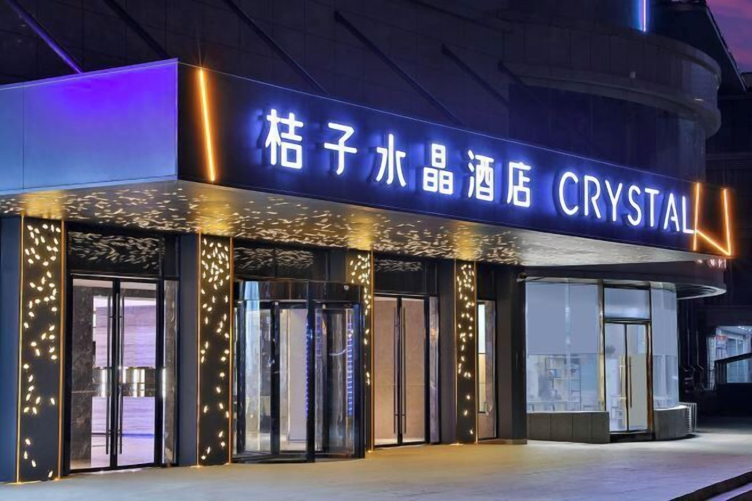A hotel entrance with illuminated signage and decorative lighting.