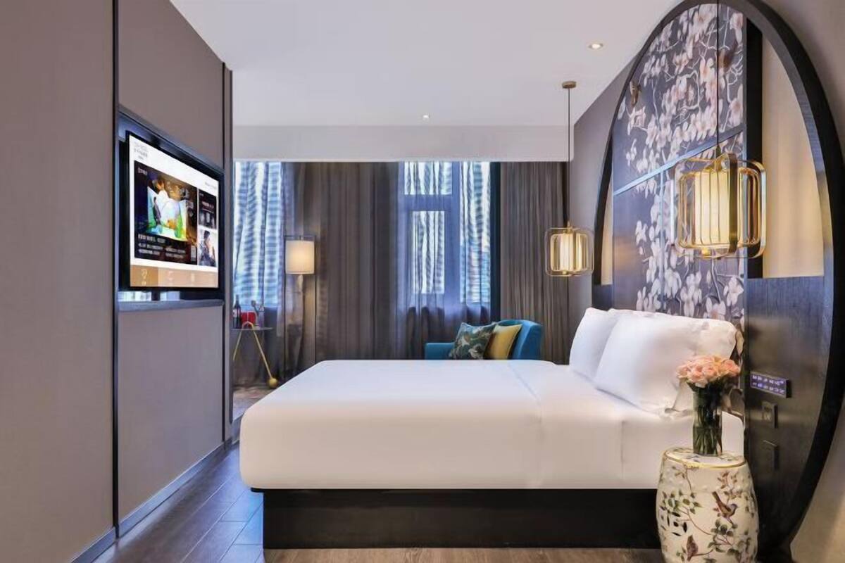 A modern hotel room with a large bed, a television, and a decorative vase.