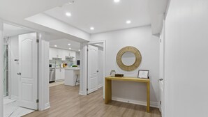 Un interior moderno con zona de cocina, suelo de madera y un espejo decorativo en la pared.