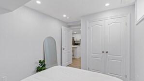 Un dormitorio con cama, espejo y puerta que da a una cocina.