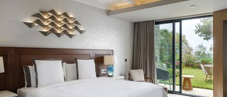 Une chambre d’hôtel moderne dotée d’un grand lit, d’un ventilateur de plafond, d’une vue sur le jardin et d’une grande fenêtre.