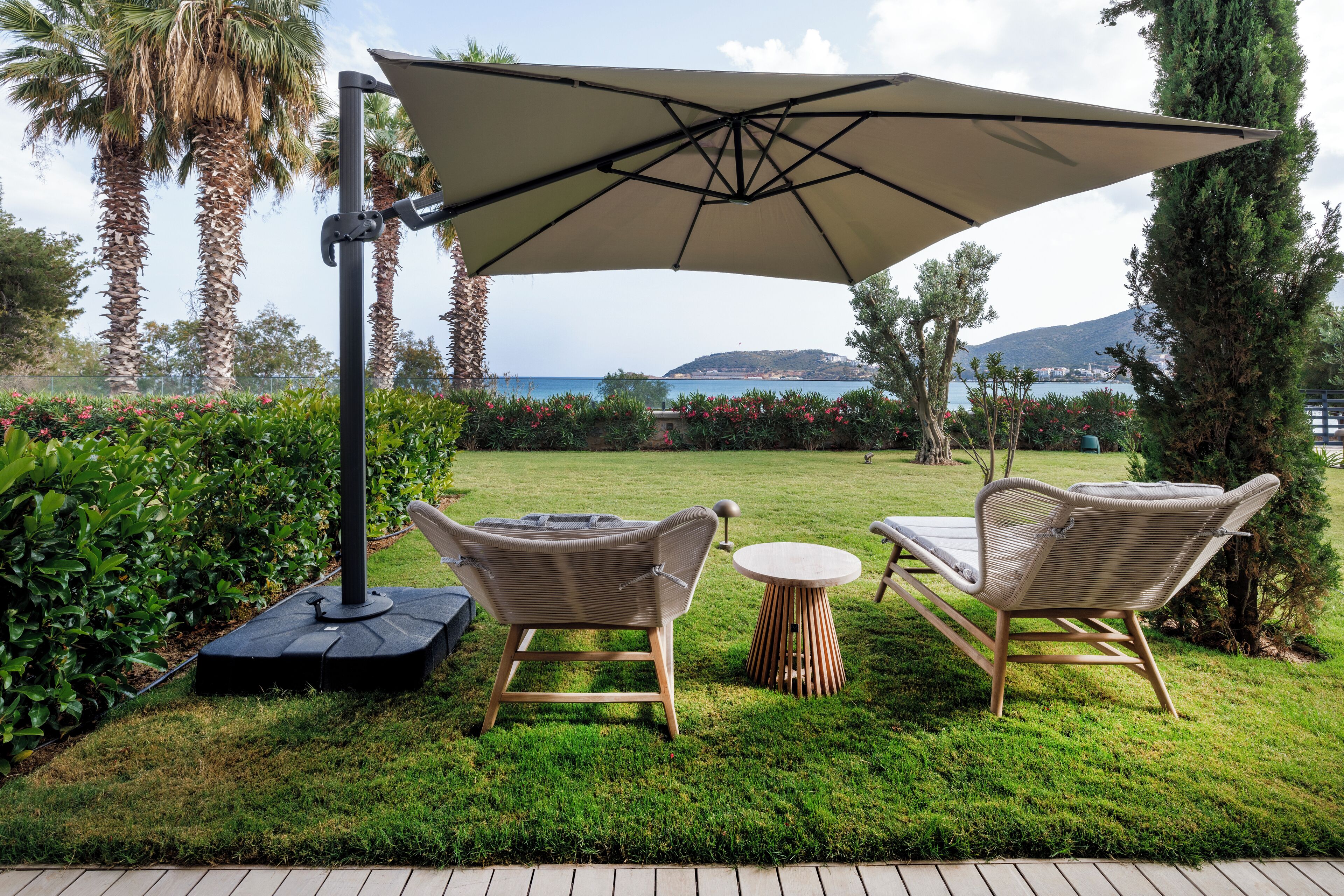 A patio with wicker furniture, a large umbrella, and a view of the sea.