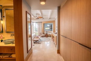Quarto de hotel moderno com piso de madeira, uma mesa de jantar redonda, um sofá e um ventilador de teto.