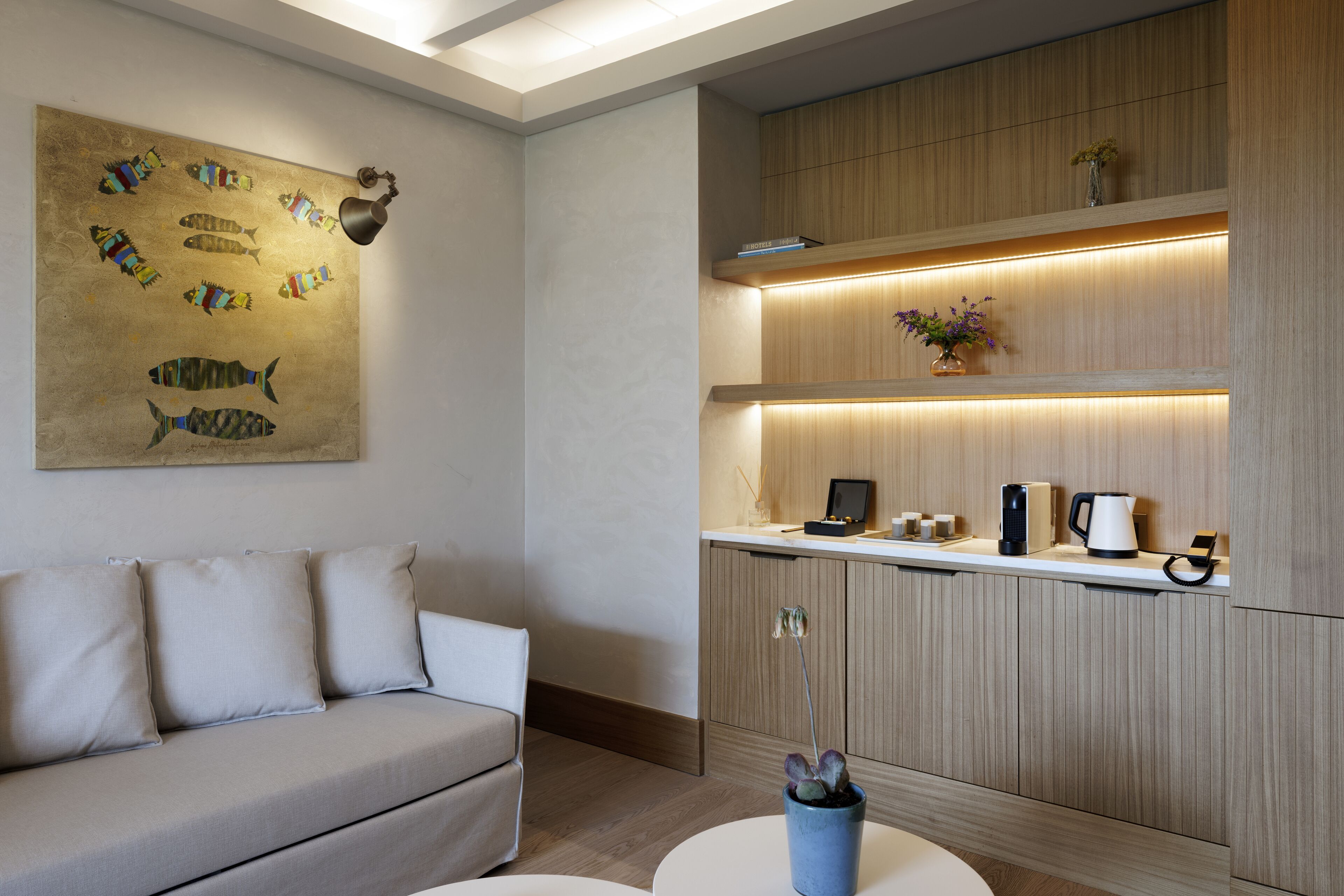 Una sala de estar moderna con un sofá, una mesa de centro y un estante montado en la pared con objetos decorativos.