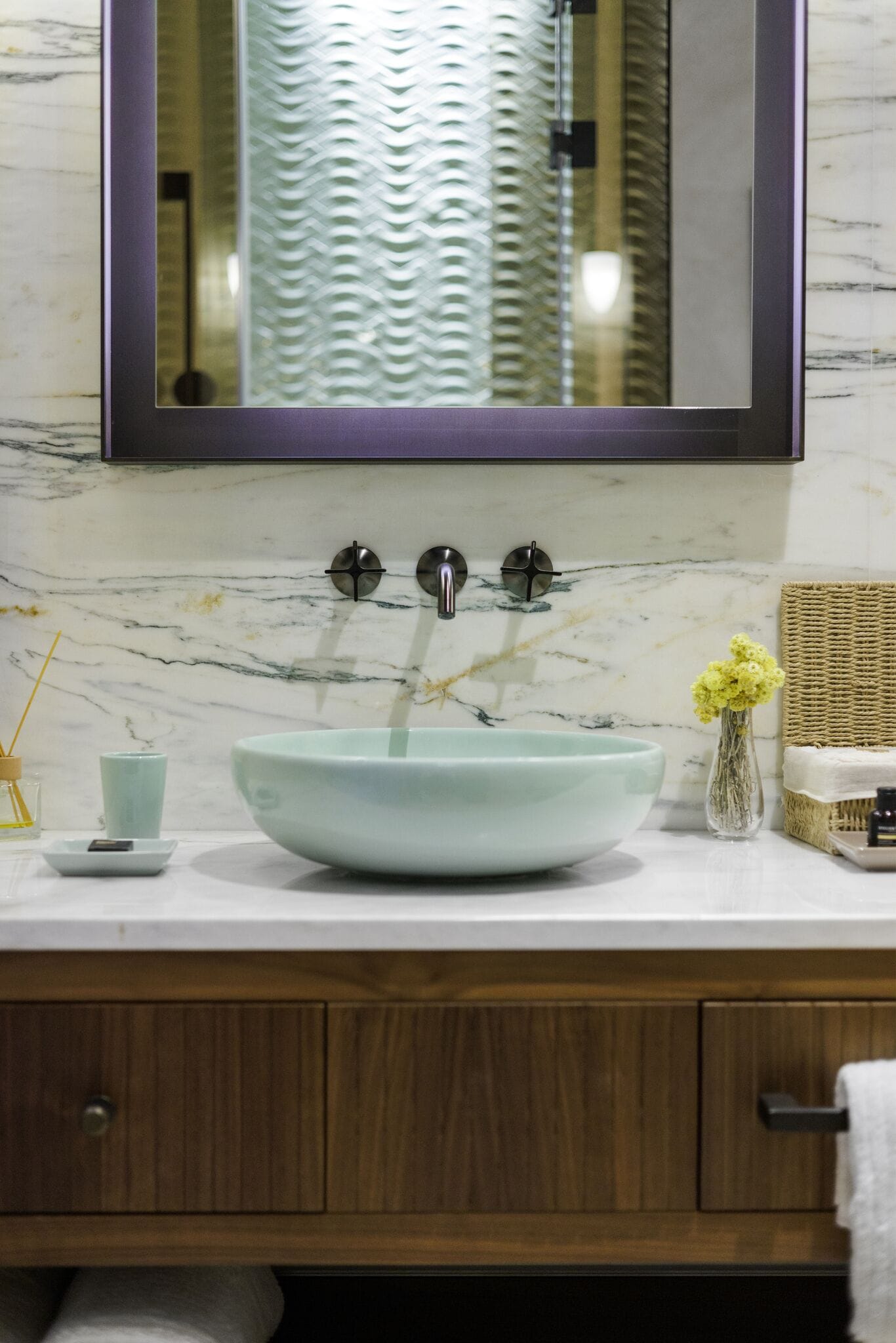 A bathroom with a marble sink, wooden vanity, and a mirror above the sink.