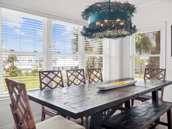 Enjoy meals with a view in this dining area, featuring a long table and wicker chairs.