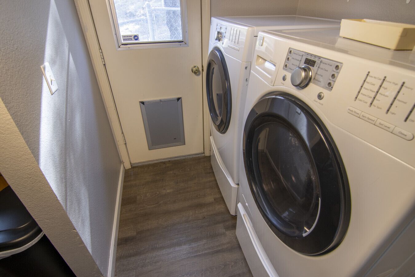A laundry room with two front-loading washing machines and a small window above the door.