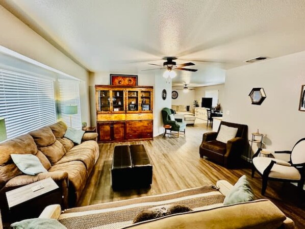 A living room with a brown leather sofa, a wooden cabinet, and a ceiling fan.
